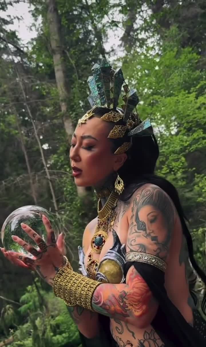 AKASHAH holding a crystal sphere in a forest in the supplied Distant Visions recording